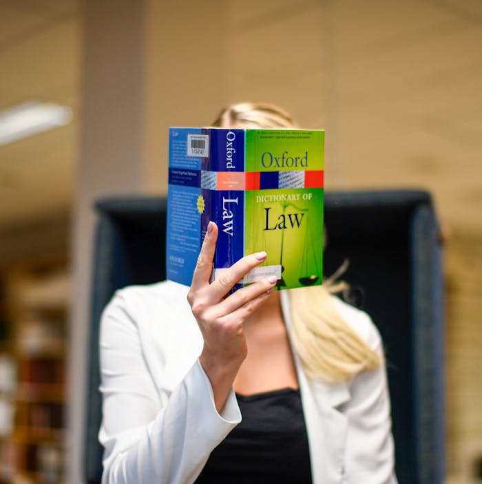 services-04 Blonde woman reading the Oxford Dictionary of Law in a university library setting.