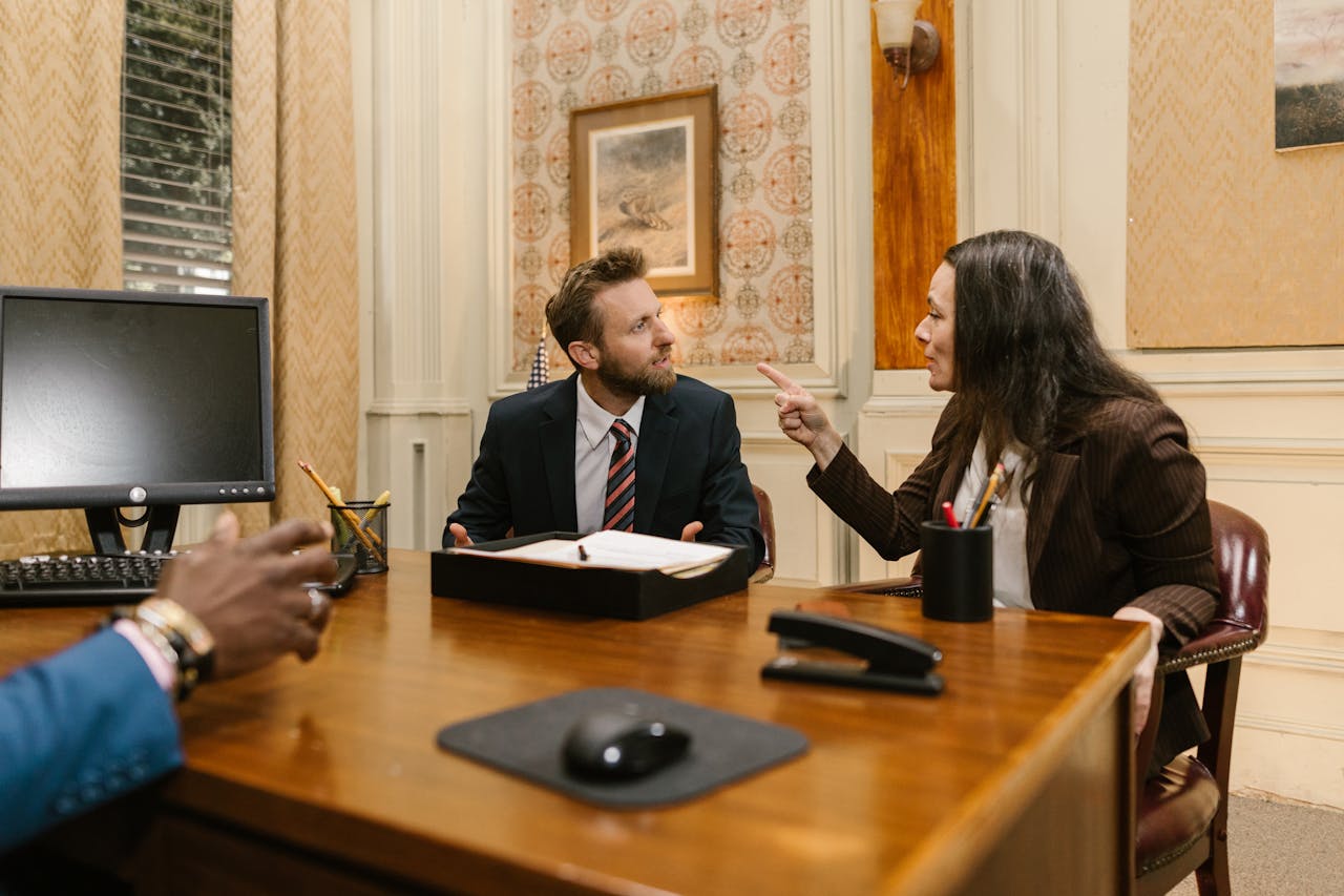 gallery-4 Professionals engaged in a serious discussion inside a law office with a computer on the desk.