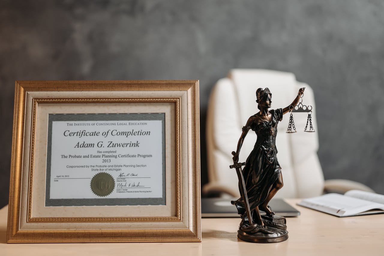 about-01 A framed legal certificate and Lady Justice figurine on a desk in a law office setting.